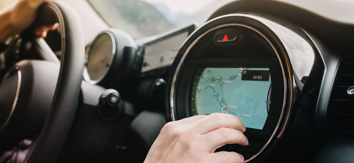 Man sitting in the car with black interior and looking at the new route laid by the navigator. Driver waiting for the itinerary to be made up before journey..